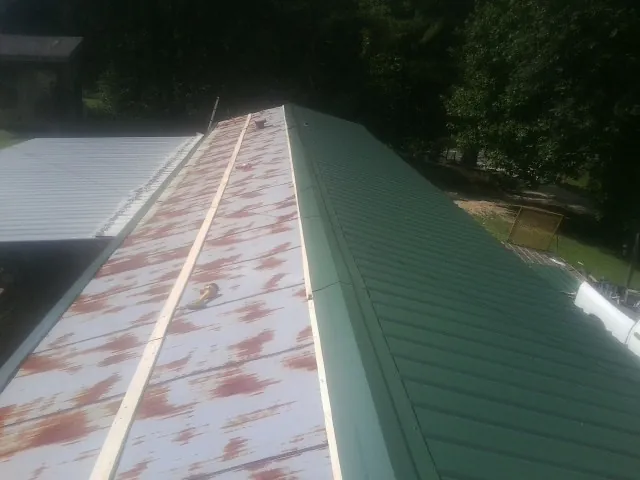 Old rusted panels beside newly installed green metal roofing — Wind Damage Roof Repair by Roofing Brothers in Deer Trail