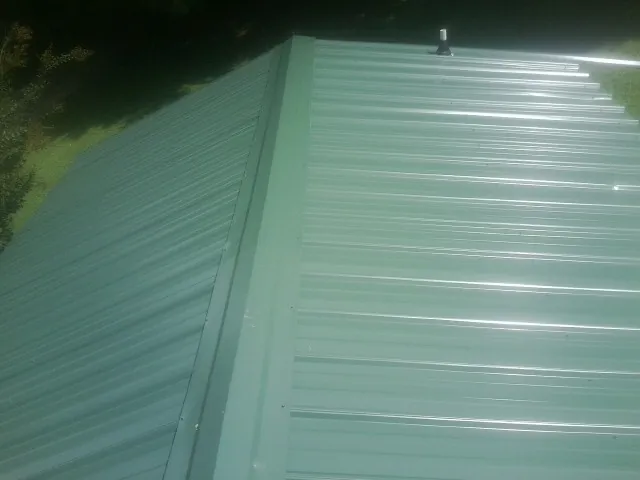 New green metal panels meeting at the ridge of a roof — Flat Roof Repair work by our crew in Deer Trail