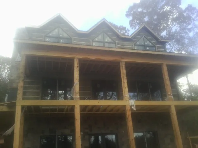 Dormers and porch framing on a large log home under construction — Roof Coating work by our crew in Deer Trail