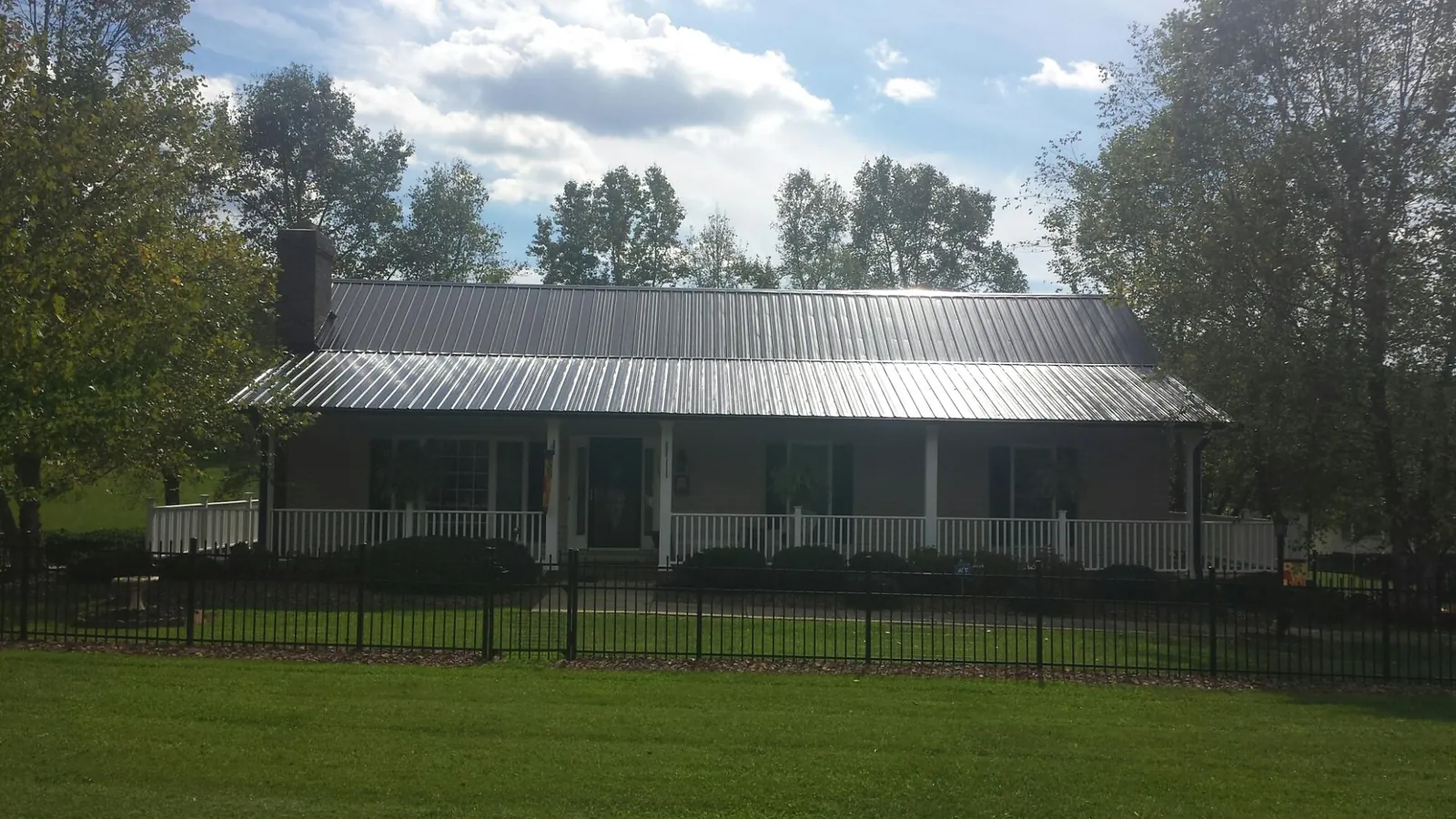 Gray metal roof on a brick ranch with a full width front porch — Gutter Guard Installation work by our crew in Deer Trail