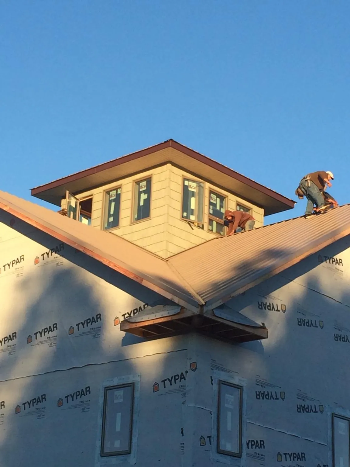 Roofers working around a rooftop cupola on a new metal roof at sunset — Roof Waterproofing in Deer Trail by Roofing Brothers